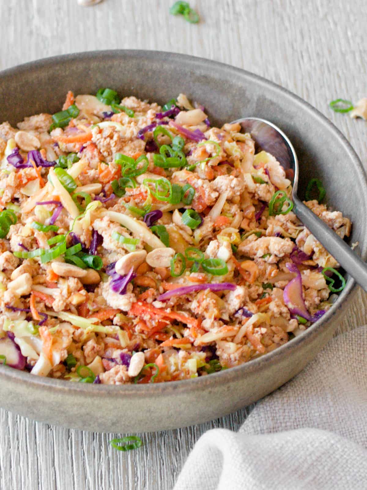 Side angle of egg roll in a bowl with serving spoon.