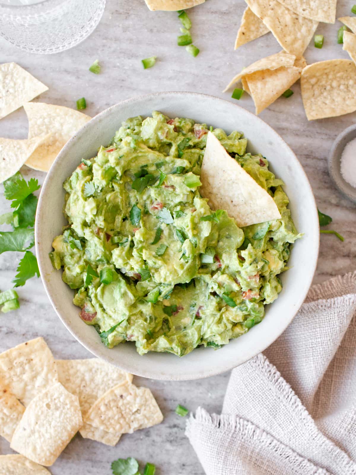 Bowl of guacamole with tortilla chips and towel.