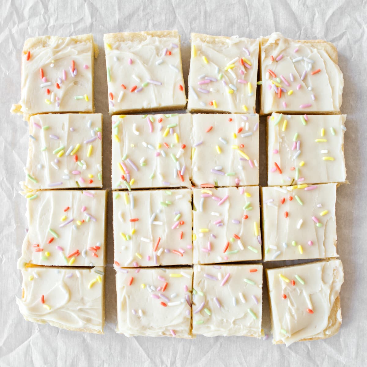 Sugar cookie bars with frosting and sprinkles, sliced and ready to be served.