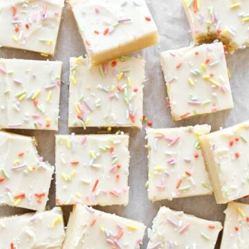 Sliced frosted sugar cookie bars on parchment paper.