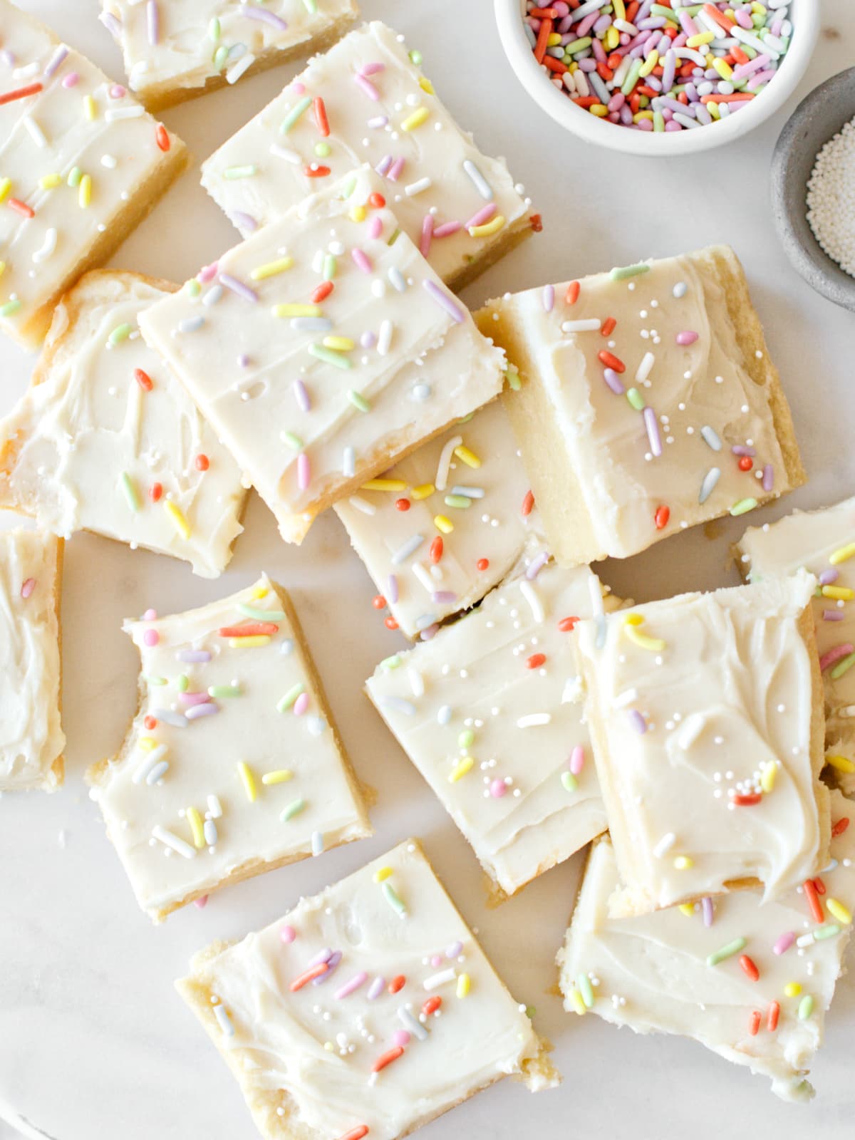 Sugar cookie bars on platter with a bowl of sprinkles.