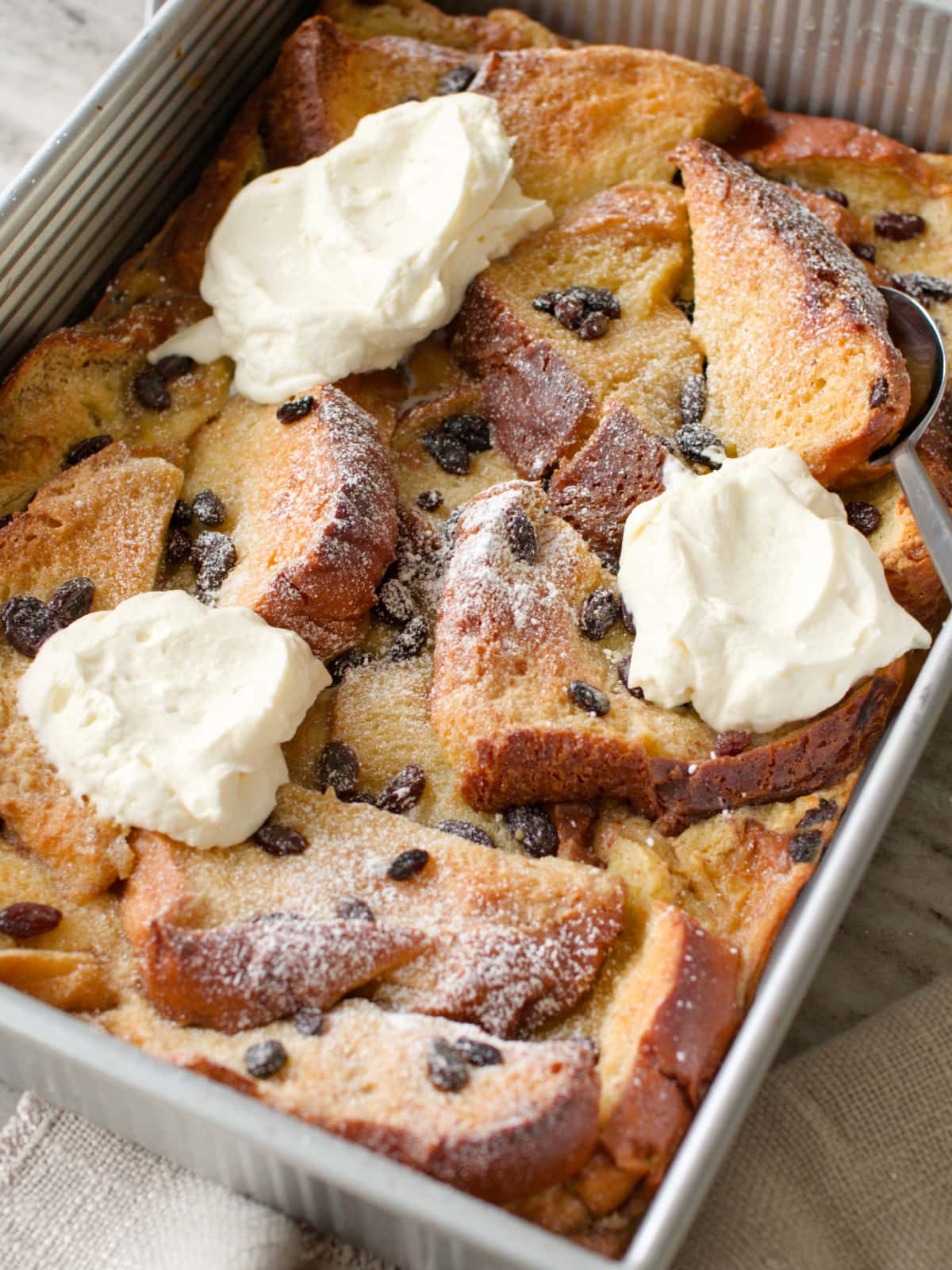 Side angle of bread and butter pudding with serving spoon.
