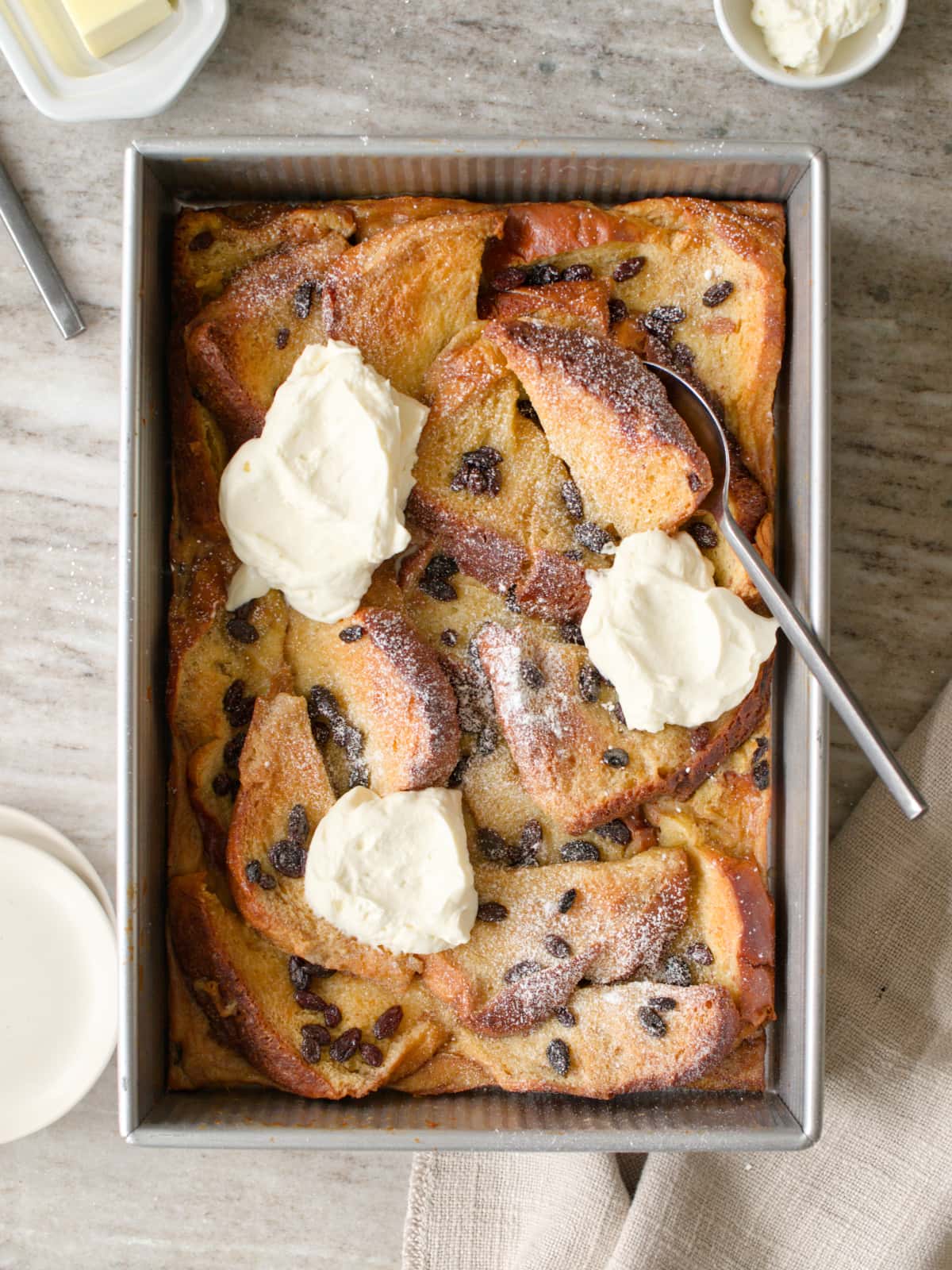 Bread and butter pudding with whipped cream and powdered sugar.