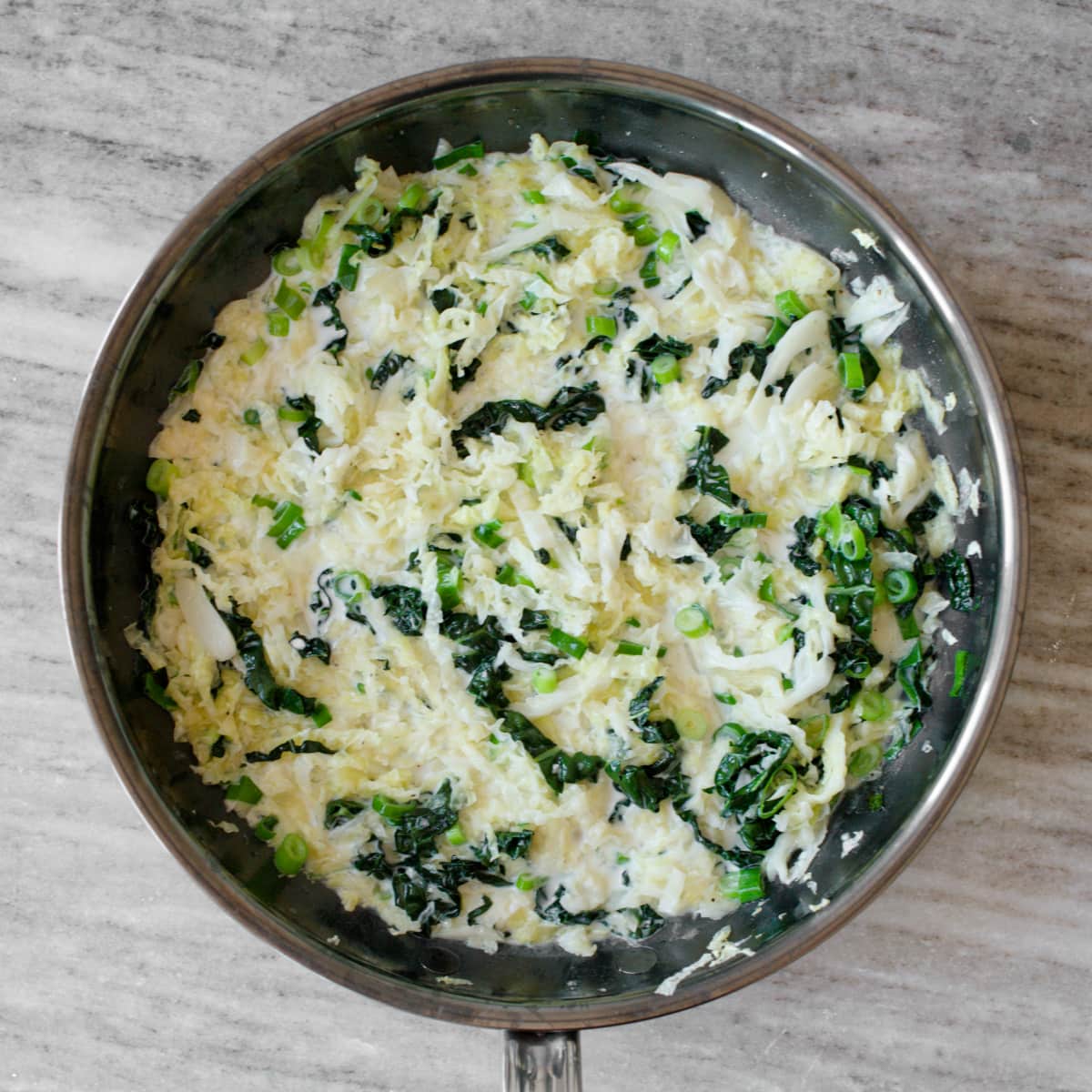 Cabbage, kale, butter, and milk cooking in skillet.