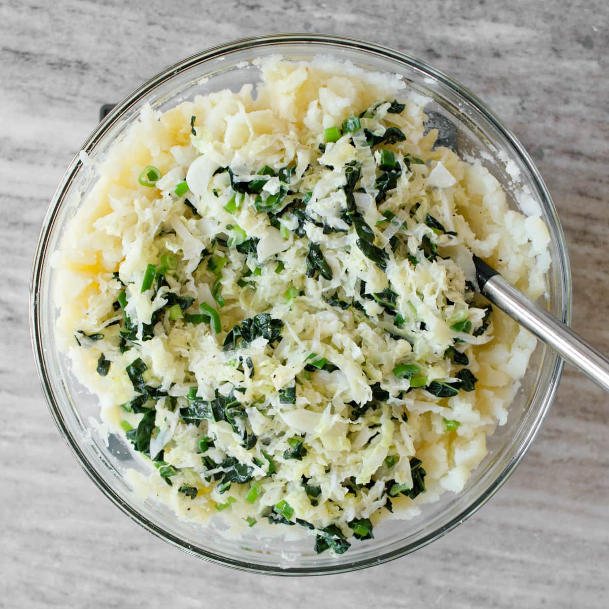 Mixing boiled potatoes with mixture.